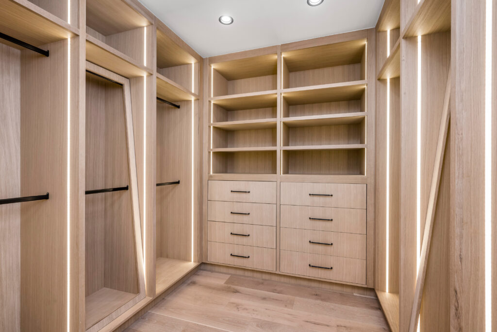 a walk in closet with wooden shelves and drawers and open shelvings
